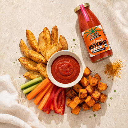Emils Bio Red Curry Ketchup wird über gegrillte Bratwurst mit knusprigen Kartoffeln gegossen